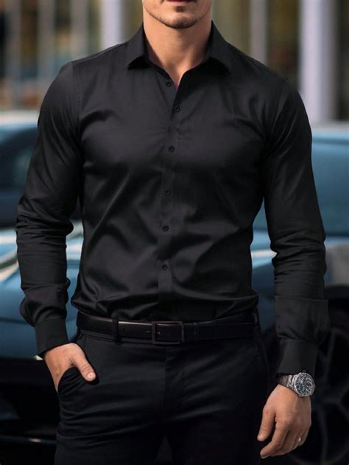 a man in black shirt and grey pants standing next to a red and white wall