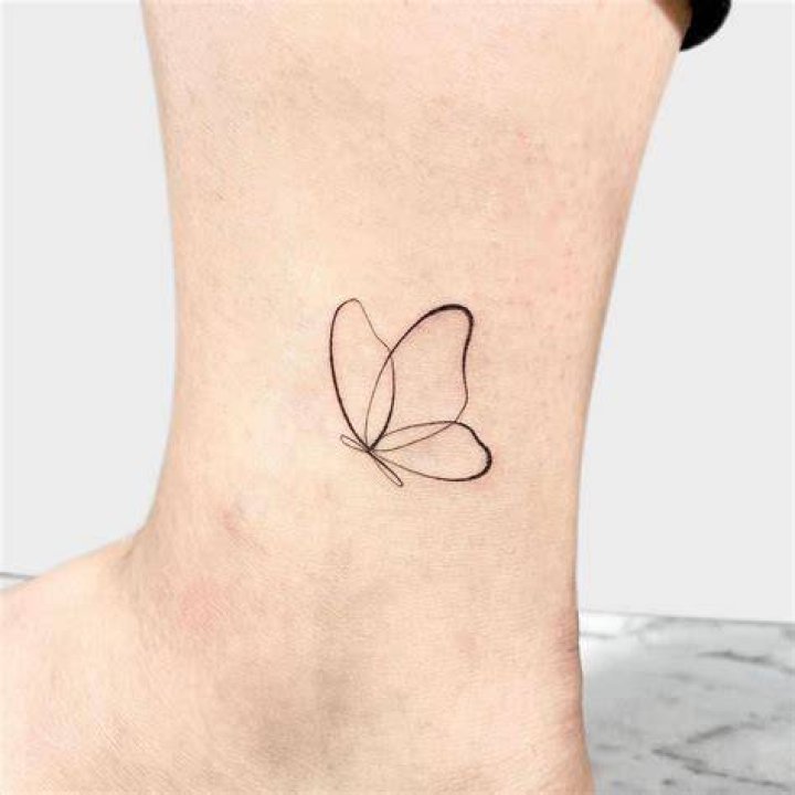 a small butterfly tattoo on the wrist is shown in black and white ink
