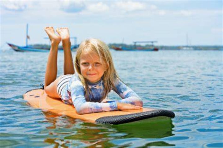 A young girl boogie-boards on floodwater at a campground in Mangawhai, Northland. Photo / Emma Simpson