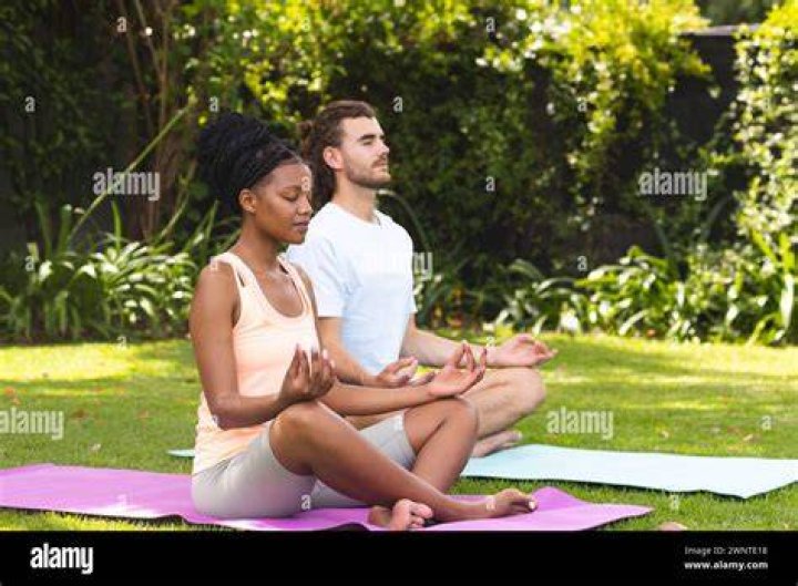 African man practice yoga in the butterfly position in yoga class african man practice yoga in the butterfly position in yoga class male sitting on an exercise mat and stretches inner thighs while holding his feet for flexibility