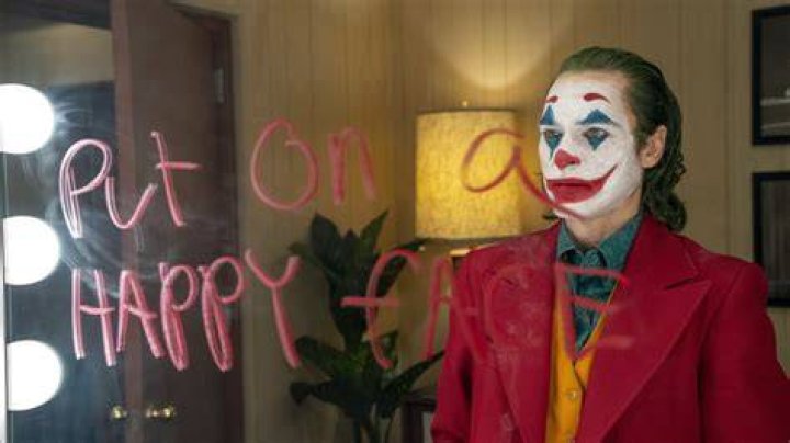 Arthur Fleck in clown make-up looking down in Joker