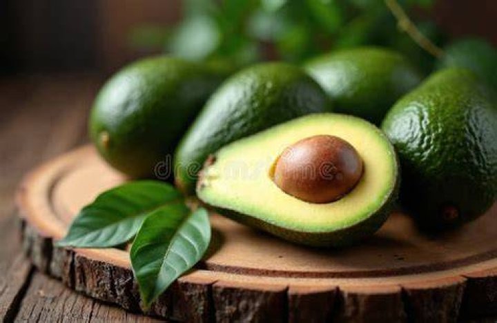 avocados whole on old wooden background with copyspace