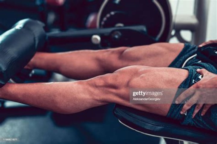 bodybuilder working leg muscles in gym