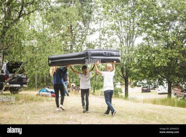 Children Carrying Inflatable Mattress While Walking Towards Car At Camping Site