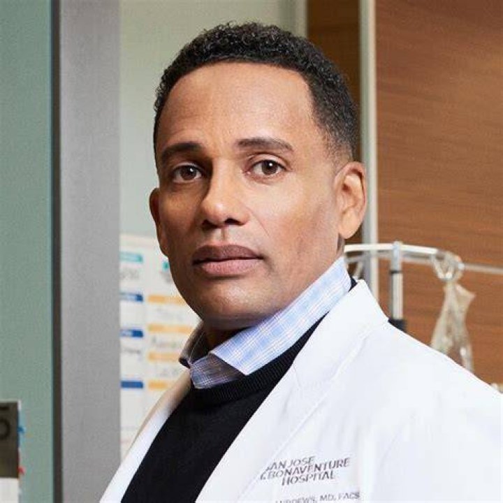 Dr. Marcus Andrews wearing a suit and smiling in The Good Doctor.