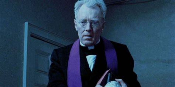 Father Merrin with a demon behind him in Dominion: Prequel To The Exorcist
