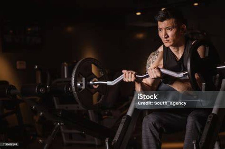 fit chinese guy practicing with dumbbells in gym