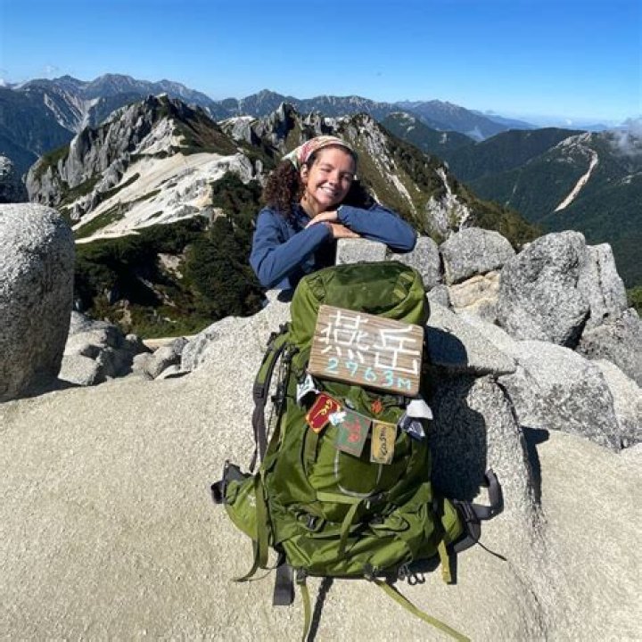Gap year backpacker trekking through a green open field