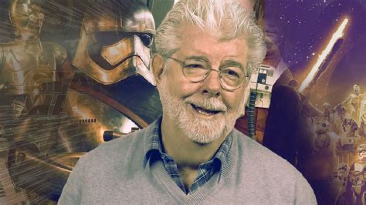 George Lucas in front of the Star Wars logo.