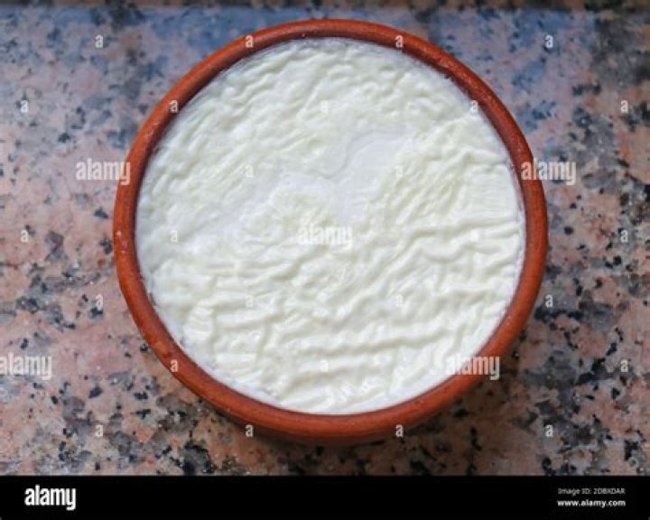 Greek yogurt in a ceramic bowl with spoons on wooden background