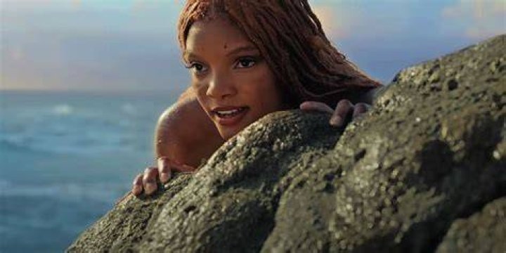 Halle Bailey as Ariel looking through a telescope in The Little Mermaid.
