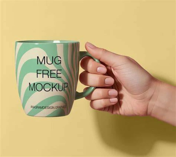 hand holding pen with mug in the background