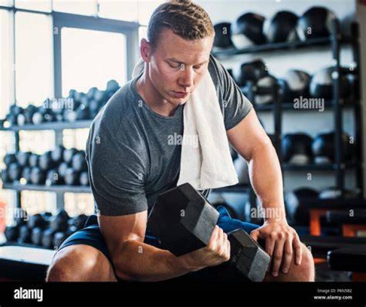 mid adult man weight lifting in gym
