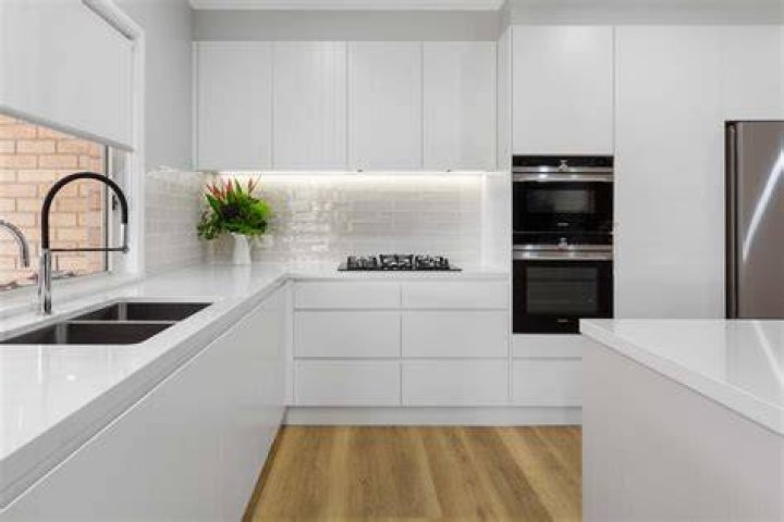 Modern kitchen with white walls illuminated by hanging lamps