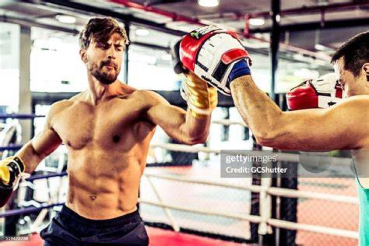 Muscular Boxer Clashing Fists With a Coach