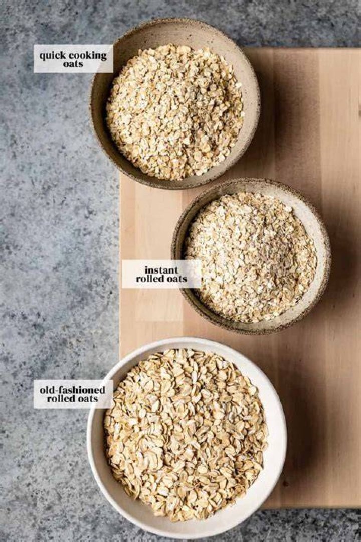 oats, rolled oats or oat flakes in wooden bowl and wooden spoon top view healthy grains, low carb diet food