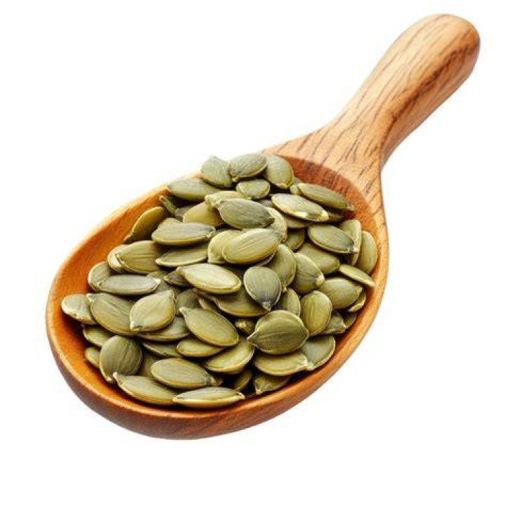 pumpkin seeds on a spoon in black background, close up