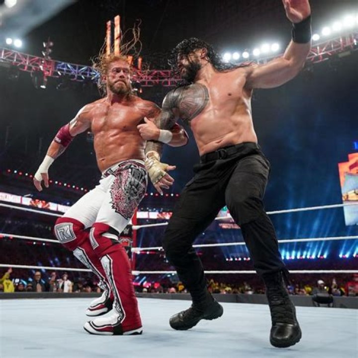 Roman Reigns and Edge fighting on the apron.