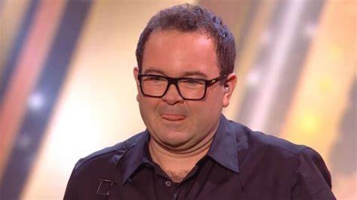 Simon looking straight at the camera with earbuds in in School Spirits