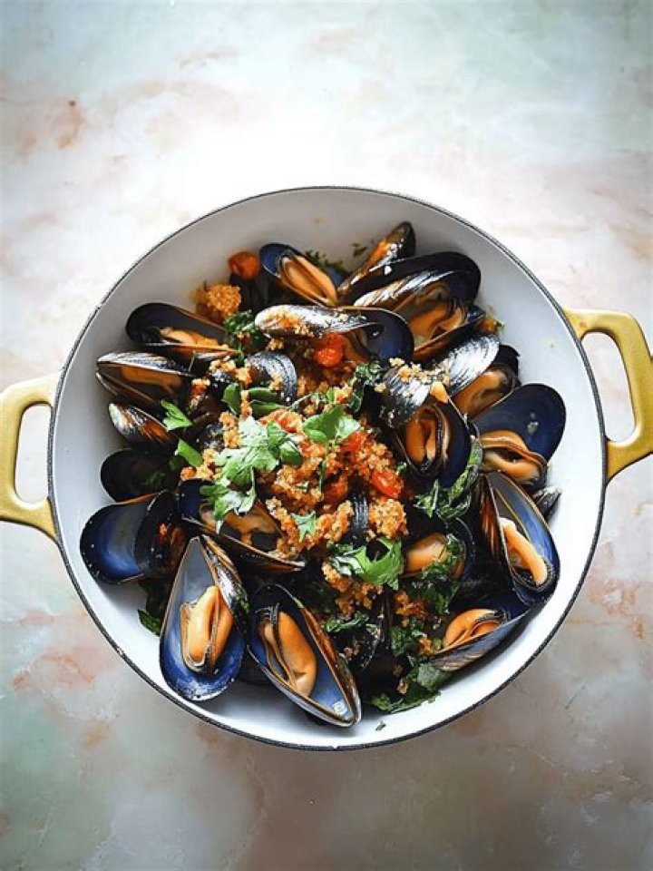 steamed mussels with herbs in gray background, top view