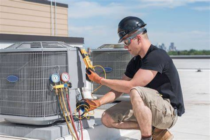 team of hvac installers repairing central air conditioning system outside of house