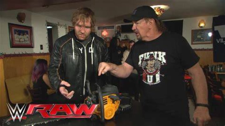 Terry Funk gives Dean Ambrose a chainsaw