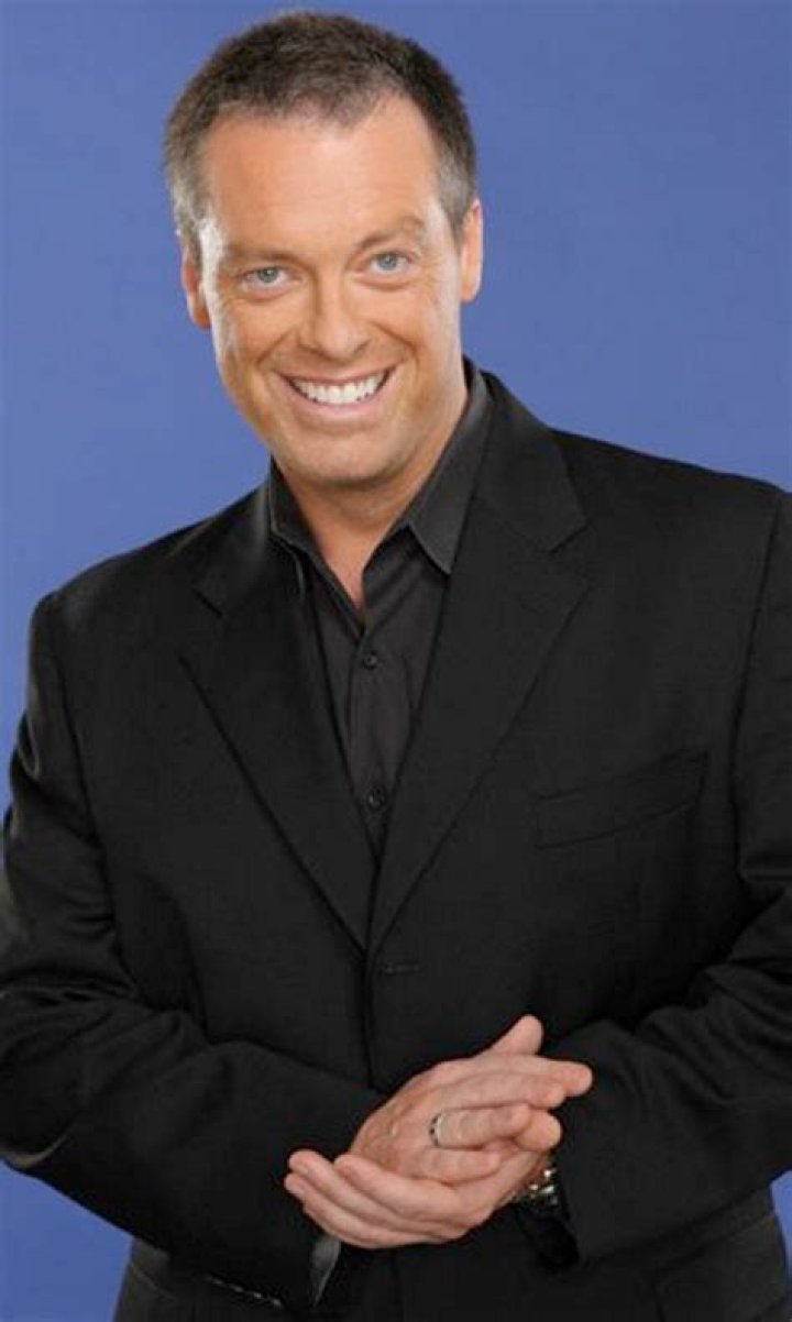 Todd newton with his hands raised and smiling in Press Your Luck with the Whammy creature on his shoulder.