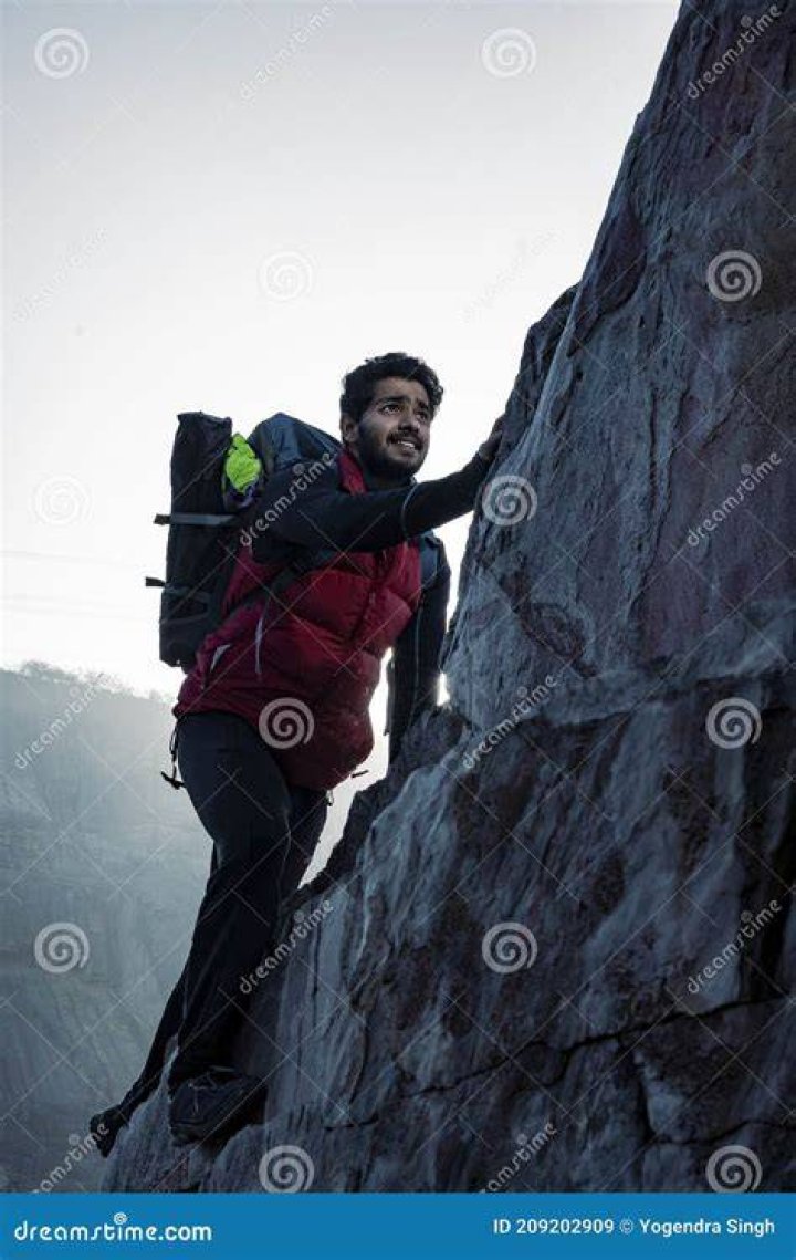 traveler climbing up a mountain while wearing a large backpack
