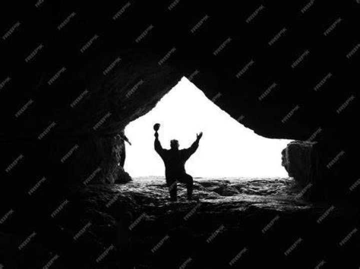 traveler sitting in cave silhouette by panoramic mountain views