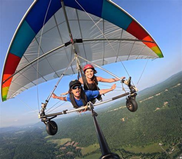 two travelers hang gliding together over green landscape