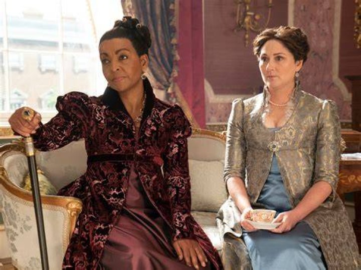Violet and Lady Danbury sitting on a bench outside and looking off into the distance on Bridgerton