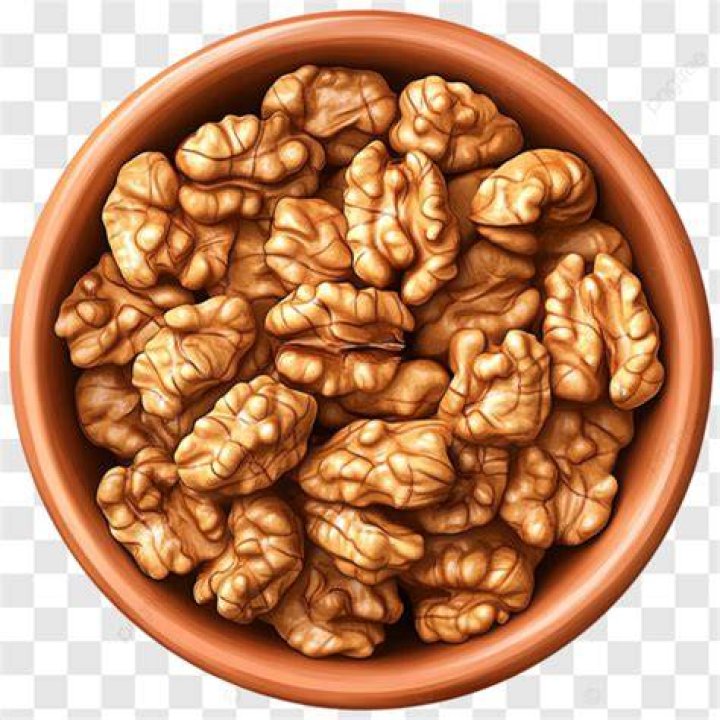 walnuts in brown bowl on wooden table, closeup view healthy food