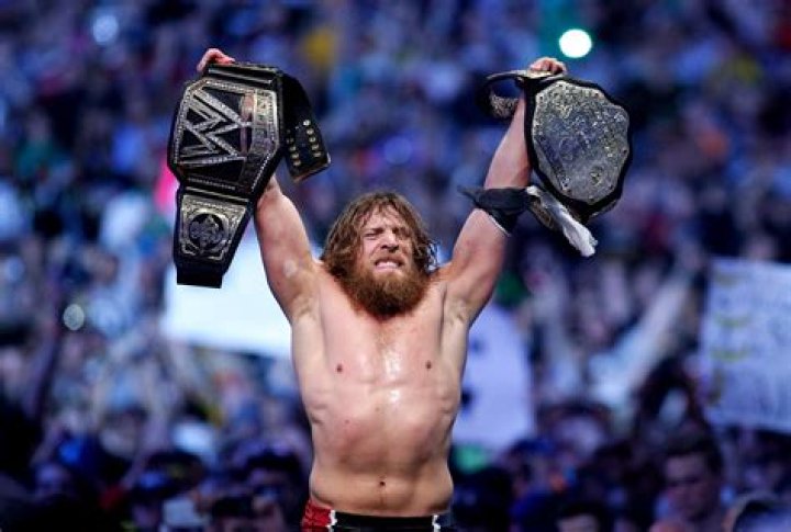 WWE Daniel Bryan Holding The WWE Championship; AJ Styles Lies Motionless