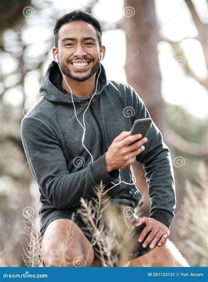 Young sporty man with earphones running on the bridge outside in a city.